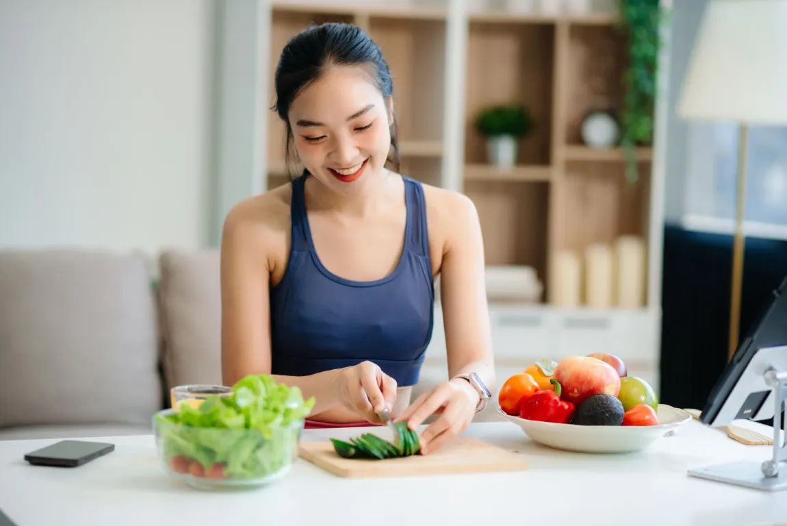 A woman eating a salad with fresh fruit